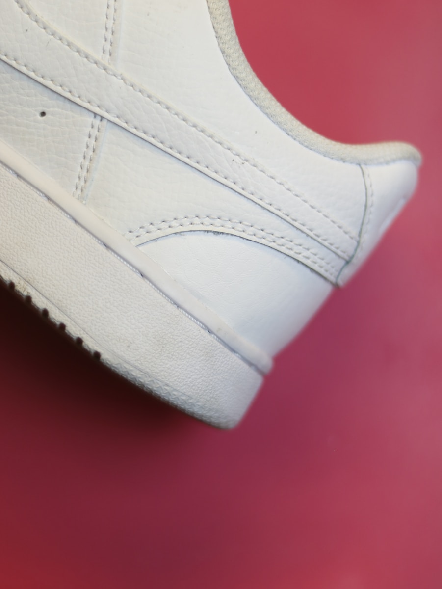 a close up of a white tennis shoe on a red surface